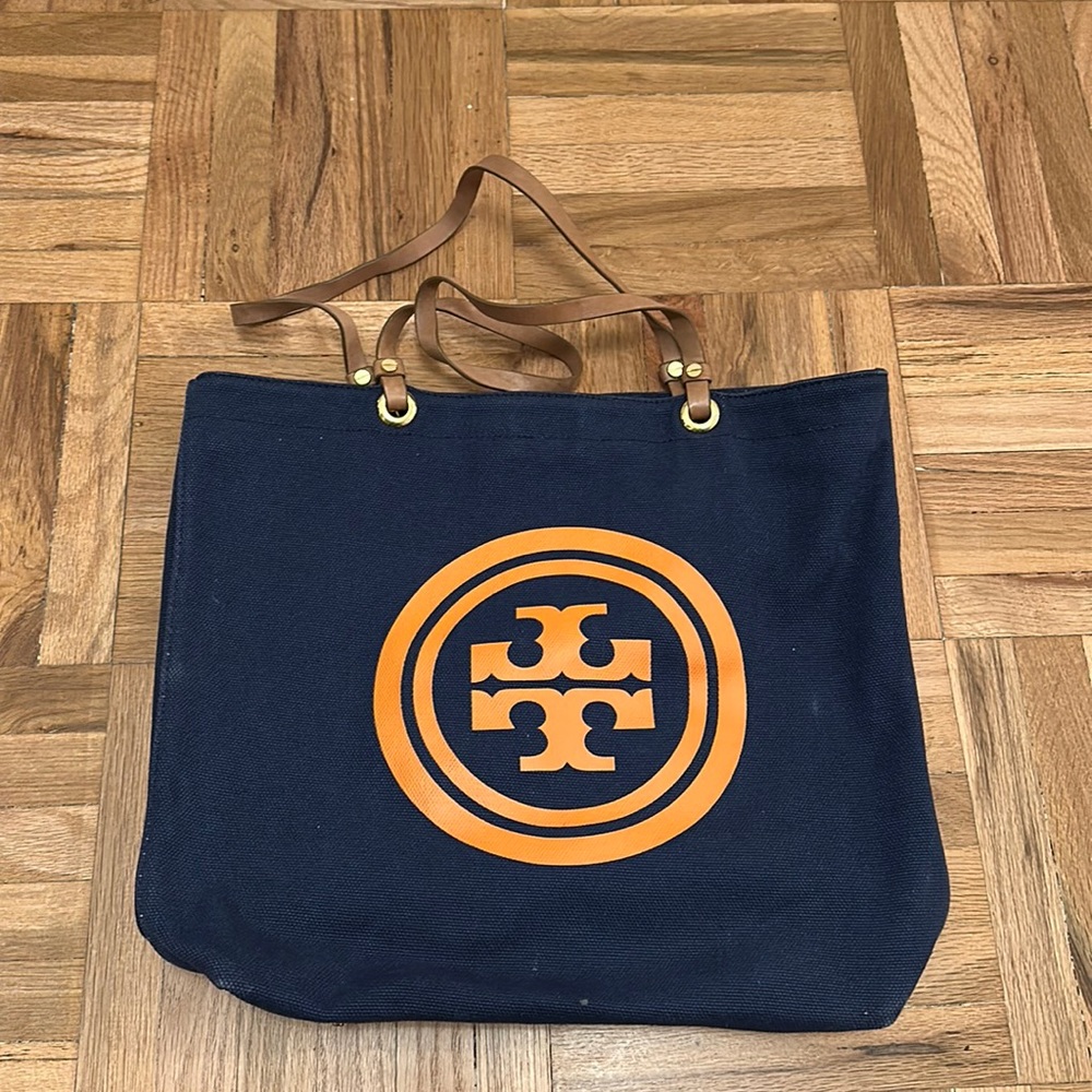 Tory Burch tote bag with orange insignia and leather shoulder strapa